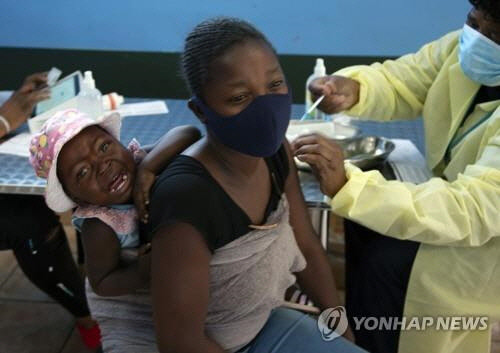 남아프리카 공화국 요하네스버그에서 아이를 업은 한 여성이 코로나19 백신을 접종하고 있다. [AP 연합뉴스 자료사진]