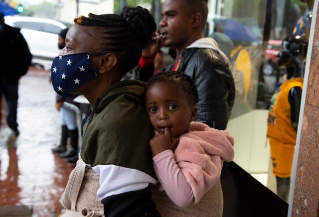 27일 남아프리카공화국 프리토리아에서 한 여성이 마스크를 하지 않은 아이를 업고 서 있다. 프리토리아=AP 연합뉴스