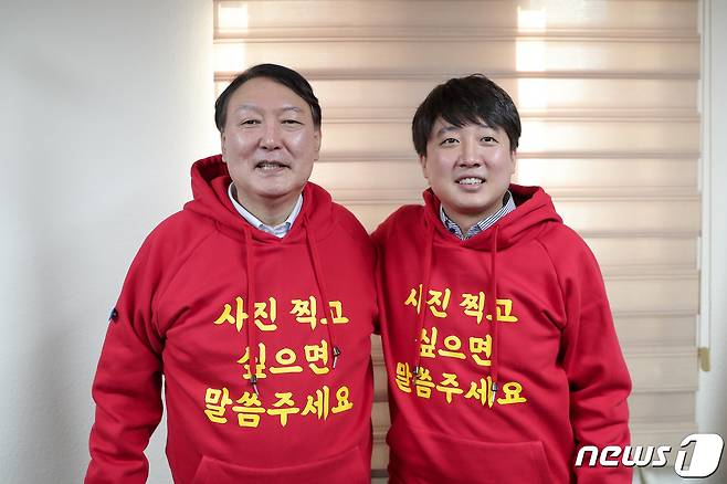 국민의힘 윤석열 대선후보와 이준석 대표가 4일 오전 부산 수영구 국민의힘 부산시당에서 열린 선거대책회의에서 '사진 찍고 싶으면 말씀주세요' 문구가 적힌 빨간색 후드티를 선보이고 있다.(국민의힘 제공)© 뉴스1