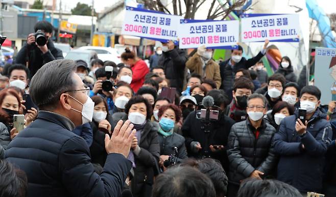 더불어민주당 이재명 대선후보가 4일 전북 군산시 공설시장을 방문, 시민들에게 지지를 호소할 때 지지자들이 "소년공의 꿈을 3040이 응원합니다"라는 손피켓을 들고 있다. / 사진 = 연합뉴스