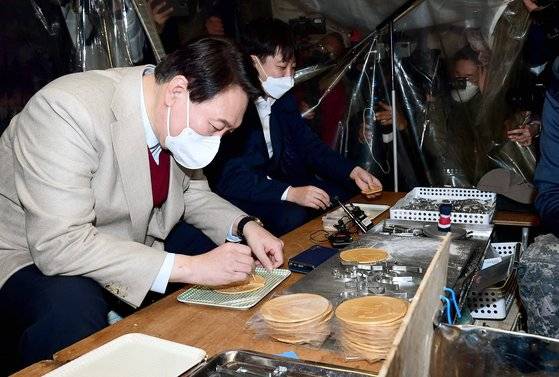 윤석열 국민의힘 대선후보와 이준석 대표가 8일 서울 종로구 대학로에서 거리인사 중 한 달고나 가게에서 달고나 뽑기 체험을 하고 있다. 뉴스1