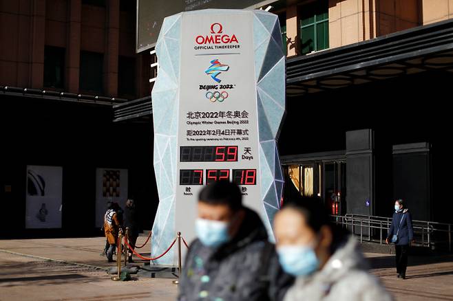 미국이 베이징 동계올림픽에 대해 ‘외교적 보이콧’ 방침을 밝힌 가운데 7일 중국 수도 베이징에서 올림픽이 59일 앞으로 다가왔음을 알리는 카운트다운 시계 앞을 마스크를 쓴 행인이 지나고 있다. 베이징 | 로이터연합뉴스