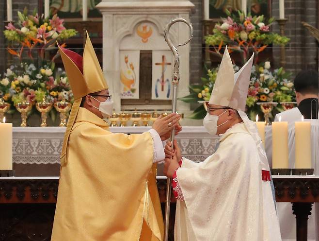 Cardinal Andrew Yeom Soo-jung (right) hands over a Baculus Pastoralis, a cane that symbolizes the Catholic archbishop, to the new archbishop of Seoul, Peter Chung Soon-taick, during an inaugural Mass at Myeongdong Cathedral in central Seoul on Wednesday. (Yonhap)