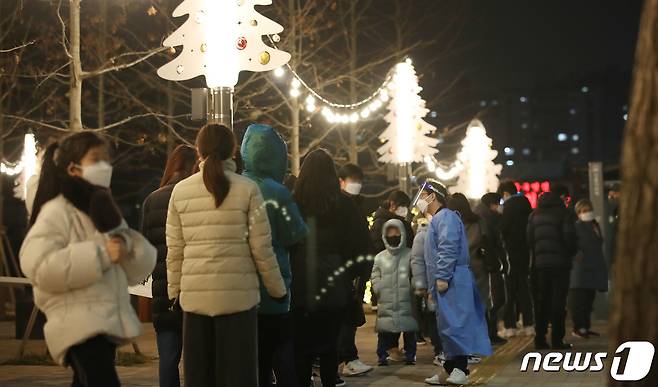 신종 코로나바이러스 감염증(코로나19) 확산으로 인해 정부가 단계적 일상회복(위드코로나)를 잠시 멈추고 강화된 방역조치를 발표한 16일 오후 서울 서대문구 신촌역 광장에 마련된 선별진료소를 찾은 시민들이 크리스마스 트리 조명 아래서 코로나19 검사를 기다리고 있다. 2021.12.16/뉴스1 © News1 임세영 기자