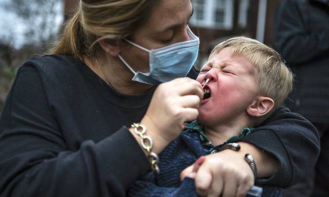 미국 펜실베이니아주 피츠버그의 스쿼럴힐 지역 거리에 주차된 신종 코로나바이러스 감염증(코로나19) 검사 차량 앞에서 한 여성이 아들의 검사를 돕고 있다. 피츠버그 포스트 가제트 제공