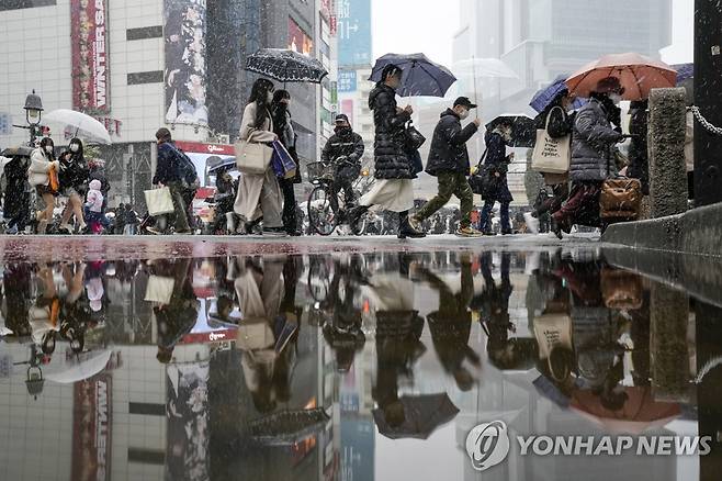 눈 내리는 도쿄 (도쿄 AP=연합뉴스) 6일 일본 도쿄 도심에서 눈이 내리는 가운데 행인들이 우산을 쓰고 이동하고 있다.