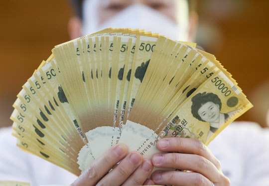 서울 중구 하나은행에서 직원이 5만원권을 펼쳐보이고 있다. 연합뉴스