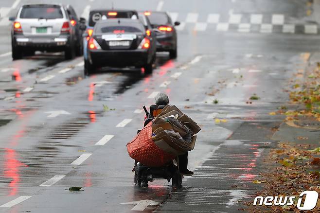 비가 그친 대구 중구 달구벌대로에서 한 노인이 전동휠체어 뒤에 폐지를 가득 실은 채 도로를 지나고 있다(사진은 기사 내용과 관련이 없음). 2021.11.8/뉴스1 © News1 공정식 기자