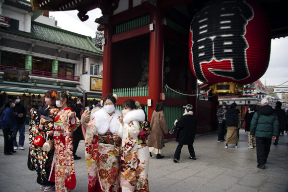 지난 10일 도쿄 아사쿠사 지구 센소지 근처에서 기모노를 입은 여성들이 마스크를 쓴 채 20세를 축하하며 셀카를 찍고 있다. 도쿄 AP 연합뉴스