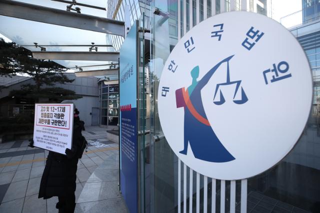 14일 서울 서초구 서울행정법원 앞에서 한 학부모가 고3 및 12~17세의 코로나19 백신 접종 중지를 각하한 재판부를 규탄하는 피켓을 들고 1인 시위를 벌이고 있다. 뉴시스