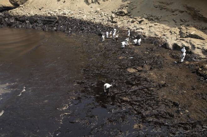 지난 19일(현지시각) 페루의 벤타니아 해변, 사람들이 기름을 치우고 있다. /로이터 연합뉴스