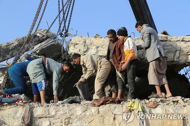 무너진 수용소 수색하는 예멘인들 (사다 로이터=연합뉴스) 21일(현지시간) 예멘 사다의 수용소에서 예멘인들이 건물 잔해를 수색하고 있다. 2022.1.22 photo@yna.co.kr