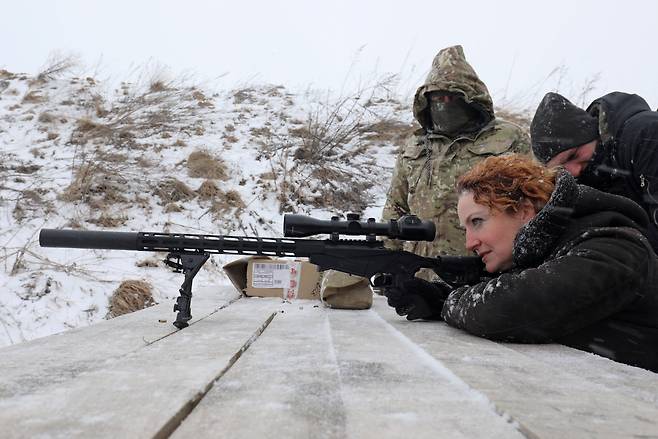 러시아와 우크라이나 간 군사적 긴장이 높아지고 있는 가운데 25일(현지 시각) 우크라이나 리비우시 외곽에서 기간산업과 공공부문 종사자들이 군사 훈련을 받은 과정에서 한 여성이 소총을 조준하고 있다. 러시아군은 최근 우크라이나를 3면에서 포위한 형태로 병력과 장비를 집결시켜 양국 간 긴장이 고조되고 있다. /로이터 연합뉴스