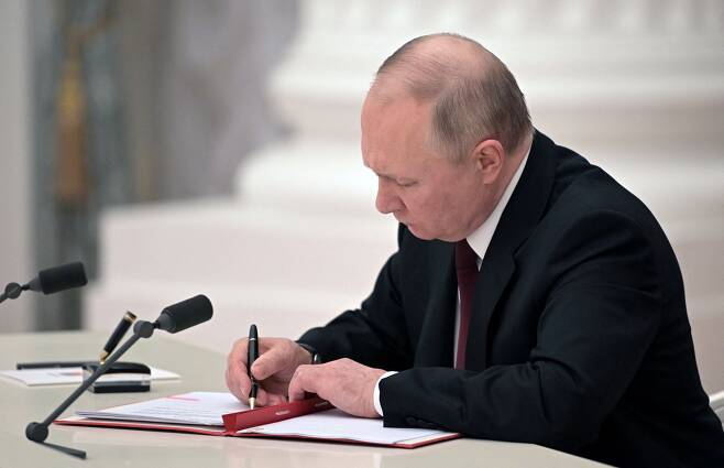 블라디미르 푸틴 러시아 대통령이 21일 러시아 모스크바에서 우크라이나 동부에서 러시아가 지원하는 두 개의 분리 지역을 독립 법인으로 인정하는 법령을 포함한 문서에 서명하고 있다./로이터 연합뉴스