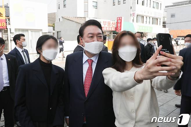 윤석열 대통령 당선인이 지난 16일 오후 서울 종로구 통의동에서 점심식사를 마친 뒤 인수위 지도부와 산책하며 만난 시민들과 함께 사진을 찍고 있다. 2022.3.16/뉴스1 © News1 국회사진취재단