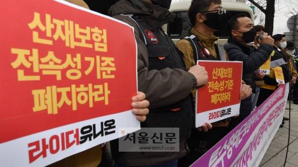 23일 오전 서울 종로구 통의동 대통령직 인수위원회 입구 인도에서 라이더유니온 주최로 열린 특수형태 근로종사자 산재보험 전속성 폐지 요구 회견에서 참석자들이 피켓을 들고 있다. 이날 회견 참석자들은 배달 종사자 등 특수행태 근로자들이 산재보험 적용을 못받는 경우가 많다며, 5월 새롭게 출범할 새정부에 대책 마련을 촉구했다. 2022.3.23 박지환기자
