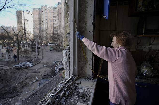 러시아군은 많은 주거용 건물을 고의로 폭격했다. 3월21일, 박살난 창문을 비닐로 가리기 위해 한 여성이 창문 크기를 재고 있다. (3월21일 키이우, AP, 연합)