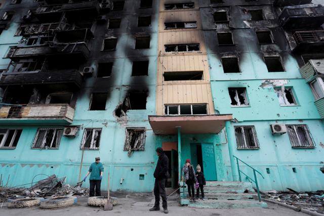 4일 우크라이나 마리우폴에서 주민들이 러시아군의 포격으로 무너져내린 아파트을 지나고 있다. 마리우폴=로이터 연합뉴스