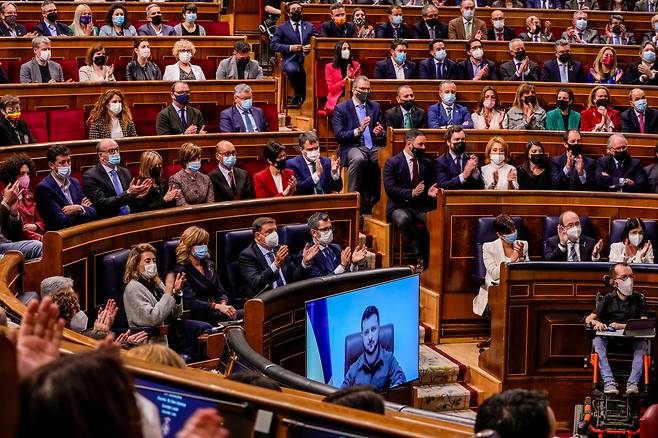 스페인 의원들이 5일(현지 시각) 수도 마드리드 의사당에서 화상 연설에 나선 볼로디미르 젤렌스키(화면) 우크라이나 대통령에게 일제히 박수를 보내고 있다. /AP 연합뉴스