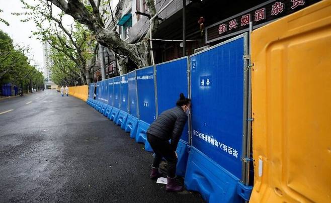 [사진: 로이터-연합] 지난 14일, 상하이의 한 봉쇄구역에 갇힌 주민이  부족한 식품을 사기 위해 장벽 틈새로 노점상 접촉을 시도하고 있다.