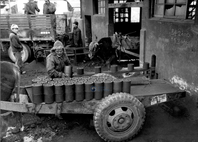 앞쪽에선 우마차(소달구지)에 연탄을 싣고, 뒤쪽에선 트럭에 연탄을 싣고 있다. 달구지 뒤편에 ‘대동연탄'이 적힌 것으로 보아 종로구 원서동 비원 근처에 위치했던 대동연탄으로 추정된다. 국가기록원 제공