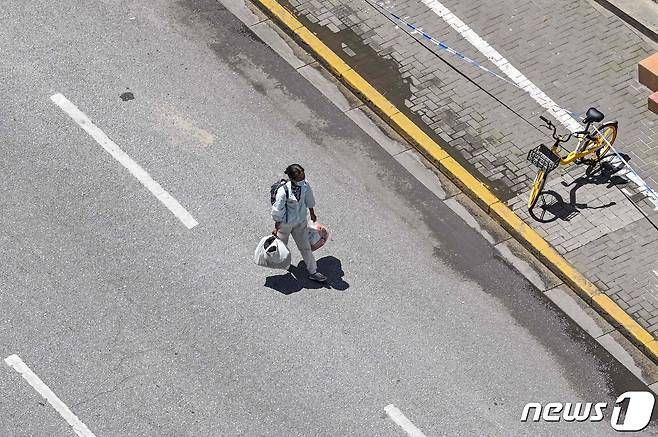 6일 (현지시간) 코로나19 봉쇄령이 내려진 중국 상하이의 텅 빈 도로에서 주민이 걸어가고 있다. 2022.5.6© AFP=뉴스1
