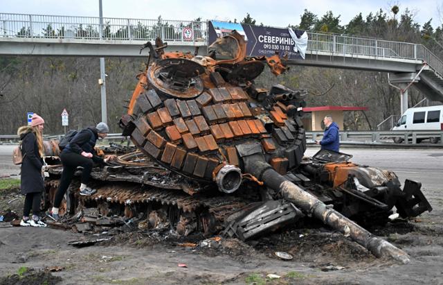 지난달 10일 우크라이나 수도 키이우 인근 부조바에서 마을 주민들이 파괴된 채 거리에 방치된 러시아군 탱크를 살펴보고 있다. 부조바=AFP 연합뉴스