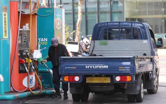 A truck driver pumps diesel into his vehicle at a gas station in Seoul on Tuesday. The government announced the expanding of its support to commercial vehicle drivers. [YONHAP]