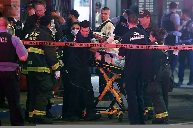 지난 14일(현지시간) 미국 시카고 시내 애덤스 스트리트에서 총격 희생자를 응급 구조대원들이 옮기고 있다. 시카고 밀레니엄파크의 유명 조형물 ‘구름문’(Cloud Gate·일명 The Bean) 인근에서 청소년 집단 간 말싸움이 총격으로 번져 16세 소년 1명이 숨지고 2명이 부상했다. AP 연합뉴스