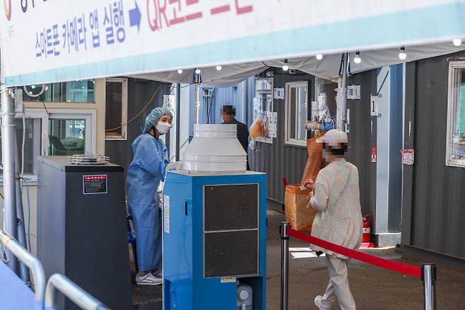 코로나19 신규 확진이 104일 만에 1만 명대를 기록한 16일 서울 중구 서울역 코로나19 선별검사소에서 시민이 PCR 검사를 받기 위해 안내를 받고 있다. 연합뉴스