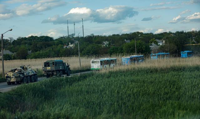 우크라이나 동남부 항구도시 마리우폴에서 항전해 온 우크라이나 병사들을 실은 버스가 17일 러시아군 차량의 감시를 받으며 러시아 점령지로 향하고 있다. EPA 연합뉴스
