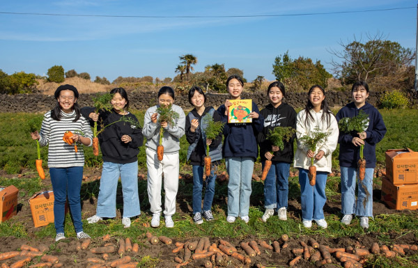 해바라기지역아동센터 아이들이 지난해 제주 구좌 당근밭에서 당근과 동화책 ‘당근이지’를 들고 환하게 웃고 있다. 구좌제일교회 제공