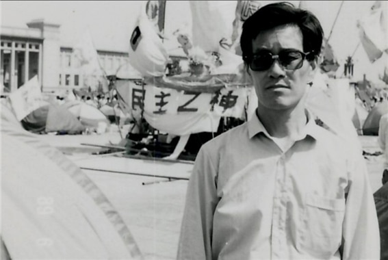 <1989년 6월, 톈안먼 광장에 민주화 운동에 적극적으로 참여하던 옌자치(嚴家其)의 모습. 배경에는 당시 학생들이 조각한 석상 아래 “민주의 신”이라는 글자가 선명히 보인다. 사진/공공부문>
