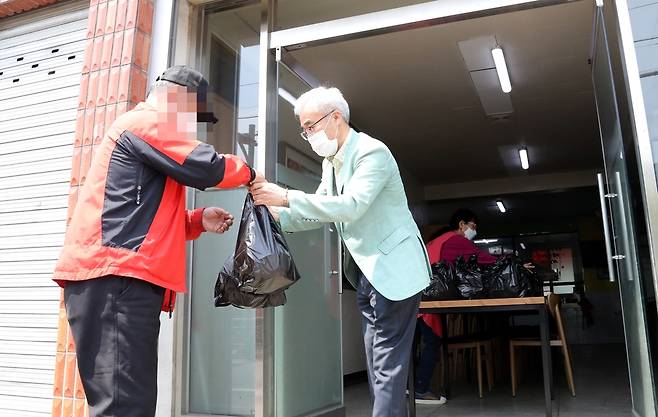 지난 20일 한 노인에게 도시락을 나눠주는 이덕희 청주교구 이사회 회장의 모습. [김형우 촬영]