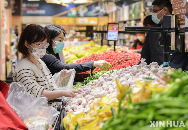 [상하이=신화/뉴시스] 코로나19 확산이 다소 완화하면서 이동제한을 풀고 있는 중국 상하이에서 10일 마스크를 착용한 시민들이 오랜만에 슈퍼마켓을 찾아 채소를 골라서 비닐봉지에 넣고 있다. 2022.05.13