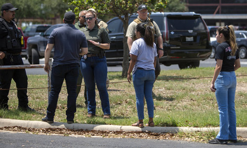 24일(현지시간) 미 텍사스주 유밸디의 롭 초등학교에서 총격이 발생해 경찰관이 주변에 모인 사람들과 얘기하고 있다. 경찰은 이 학교에서 총기 난사가 발생해 어린이 14명과 교사 1명이 숨지고 18세의 총격범은 사살됐다고 밝혔다. 유밸디=AP/뉴시스