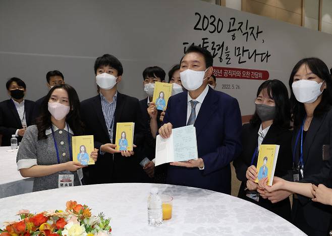 윤석열 대통령이 26일 오전 세종시 정부세종청사에서 열린 세종청사 MZ세대 공무원 간담회에서 ‘90년생 공무원이 왔다’라는 책자를 들고 참석자들과 대화하고 있다. (사진=연합뉴스)