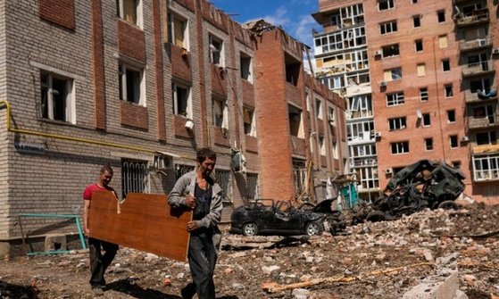 지난 24일(현지시간) 우크라이나 동부 바흐무트의 파괴된 건물 주변에서 주민들이 널빤지를 옮기고 있다. [AP=뉴시스]