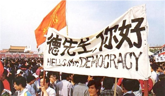 <1989년 5월 4일 톈안먼 광장의 시위 군중. “민주주의여, 안녕하십니까?” 위의 표어에 적힌 “덕선생(德先生)”은 1919년 5.4운동 당시 “민주주의”의 별칭이었다. 사진/공공부문>