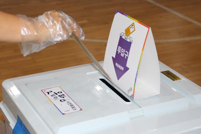 제8회 전국동시지방선거 사전투표 이틀째인 28일 오후 제주시 오라동 사전투표소가 마련된 한라체육관 보조경기장을 찾은 한 유권자가 비닐장갑을 착용한 채 투표용지를 담고 있다. 제주=뉴시스