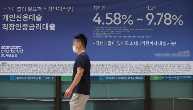 지난 25일 서울의 한 은행에 설치된 대출 관련 안내 현수막 앞으로 시민이 지나고 있다. /연합뉴스