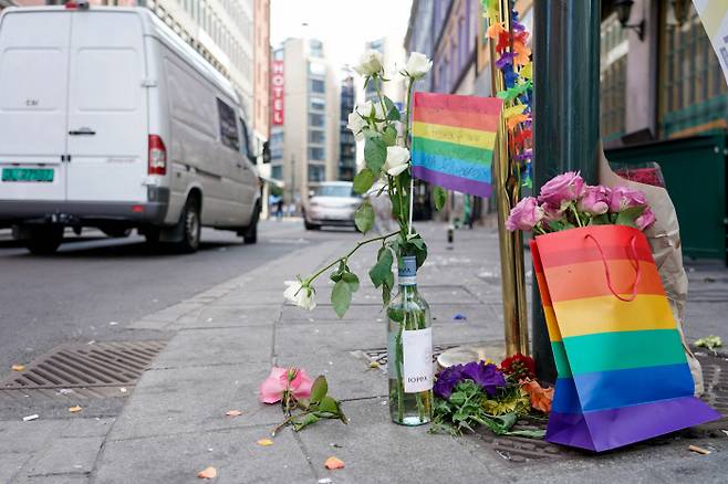 노르웨이 오슬로 중심부의 나이트클럽에서 25일 발생한 총기 난사 사건 이후 인도에 무지개 깃발과 꽃들이 놓여 있다. 로이터 제공