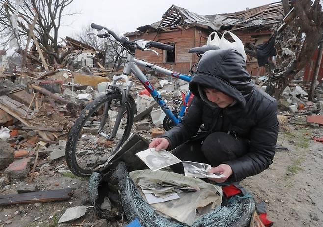 - 파괴된 잔해 더미 속에서 찾은 가족사진을 들여다보는 우크라 여성. 기사와 직접 관련 없음. EPA 연합뉴스 자료사진