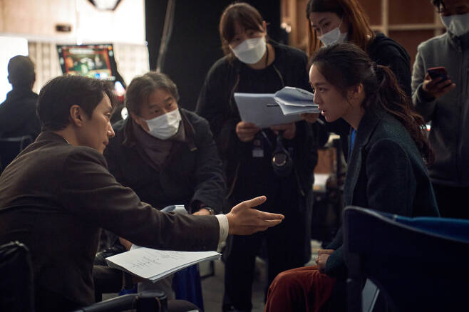 Park Chan-wook (center) speaks with the two leads Tang Wei and Park Hye-il on the set of “Decision to Leave.” (CJ ENM)