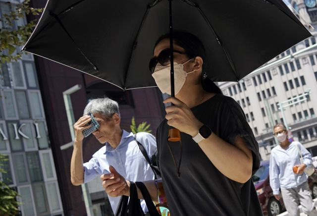 일본 도쿄 시민들이 지난 28일 양산으로 볕을 가리거나 손수건으로 땀을 닦으며 거리를 지나가고 있다. EPA연합뉴스