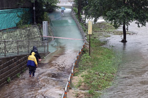 30일 하천수위 상승으로 출입이 통제된 서울 홍제천 산책로에서 우산을 쓴 한 시민이 발길을 돌리고 있다. 연합뉴스