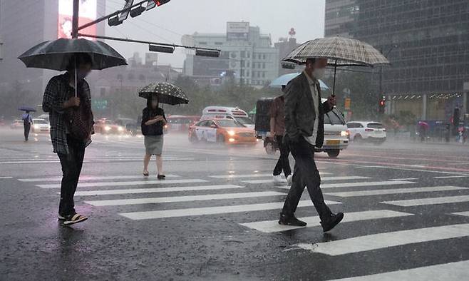 서울을 포함한 수도권에 호우특보가 발효되는 등 간밤에 많은 비가 내리면서 출근길 도심 곳곳 도로가 통제되고 있는 30일 서울 광화문 세종대로 사거리에서 시민들이 출근하고 있다. 연합뉴스
