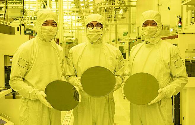 삼성 화성 반도체 공장에서 임원들이 3나노 웨이퍼를 들고 있다. 사진이 노란색인 것은 웨이퍼에 단파장 빛으로 회로를 새기는 구역이라, 품질에 영향을 주지 않으려 장파장의 노란색 조명을 쓰기 때문이다. /삼성전자