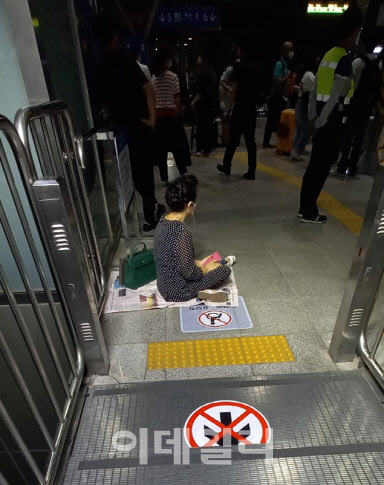 한 시민이 열차가 지연되자 1일 밤 10시30분께 서울역 바닥에서 신문을 깔고 기다리고 있다. (사진=최훈길 기자)