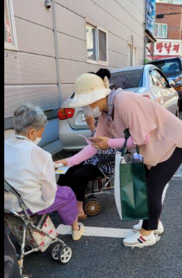 부산 예향교회 김봉정(오른쪽) 사모가 지난달 부상 동래구 교회 인근의 거리에서 한 할머니에게 전도지와 용품을 전달하고 있다.